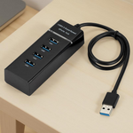 Black USB hub with multiple ports on a light wooden surface